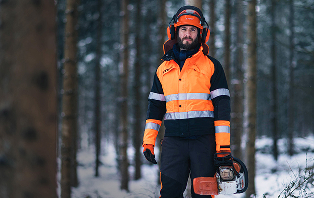 Skoghuggare går i vintrig skog med en motorsåg i handen