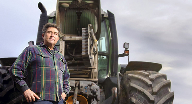 Man står framför en grön traktor